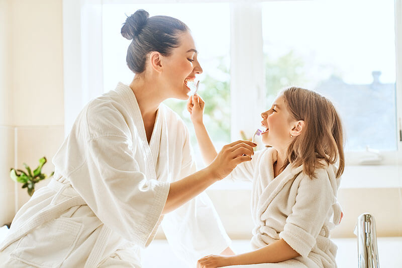 Mom and young daughter brushing each other's teeth